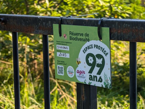 Photo montrant un affichage accroché à une barrière en fer, sur lequel est écrit zone de biodiversité